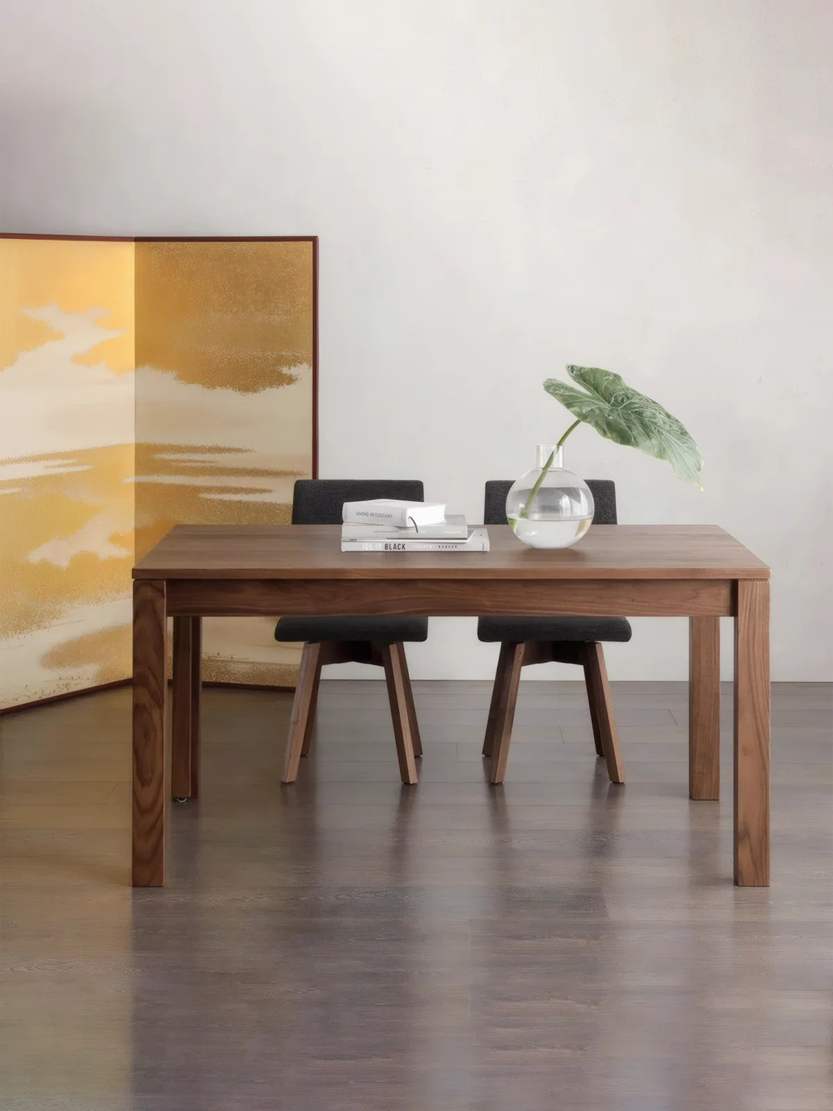 Front view of the walnut dining table with two dark upholstered chairs and a clean rectangular silhouette