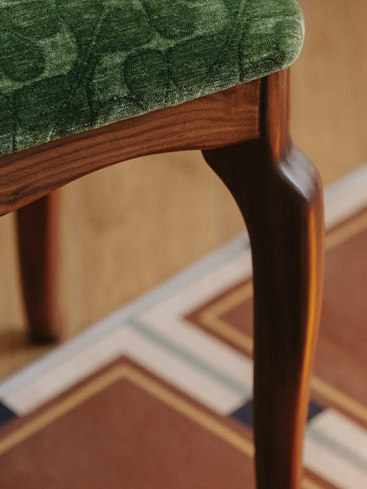Detailed shot of the elegant, curved cabriole leg and rich wood grain of The Bourbon Vanity Stool.