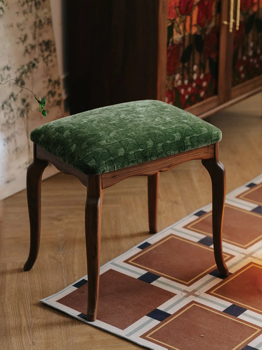 An angled view of The Bourbon Vanity Stool highlighting the contrast between the dark wood frame and the green patterned seat.