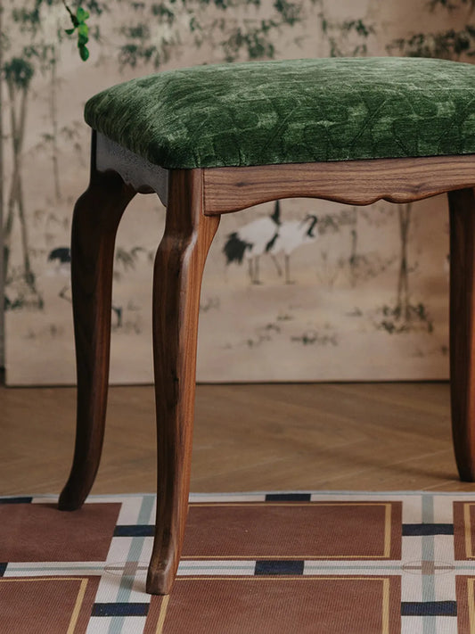 A medium shot of The Bourbon Vanity Stool focusing on the craftsmanship of the scalloped frame and the fitted velvet cushion.