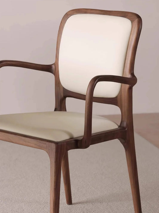 Detail of the Cael arm chair curved walnut backrest and cream upholstered back panel.