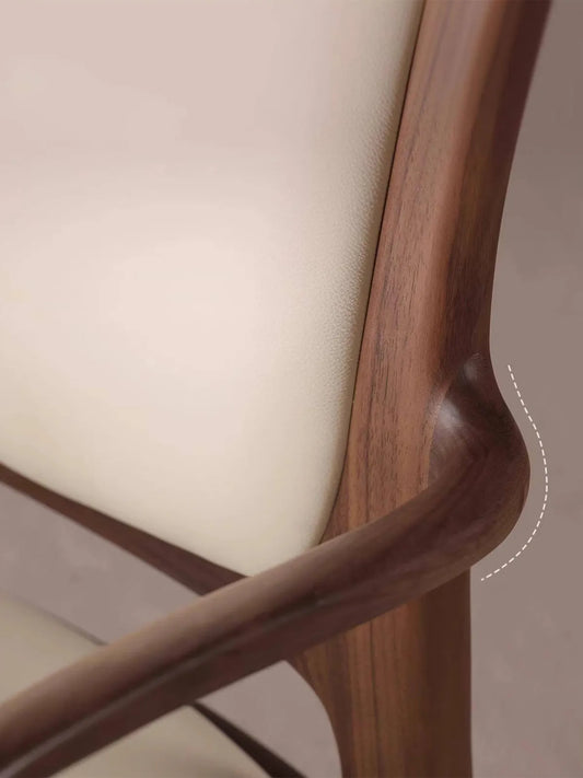 Two Cael dining arm chairs at a solid walnut dining table in a bright room with a cabinet in the background.