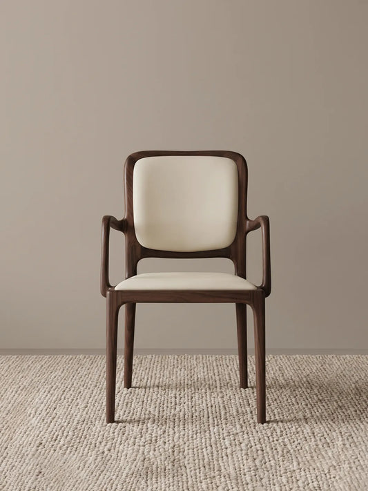 Front view of the Cael dining arm chair showing the solid walnut frame and cream upholstered seat and backrest against a neutral background.