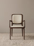 Front view of the Cael dining arm chair showing the solid walnut frame and cream upholstered seat and backrest against a neutral background.