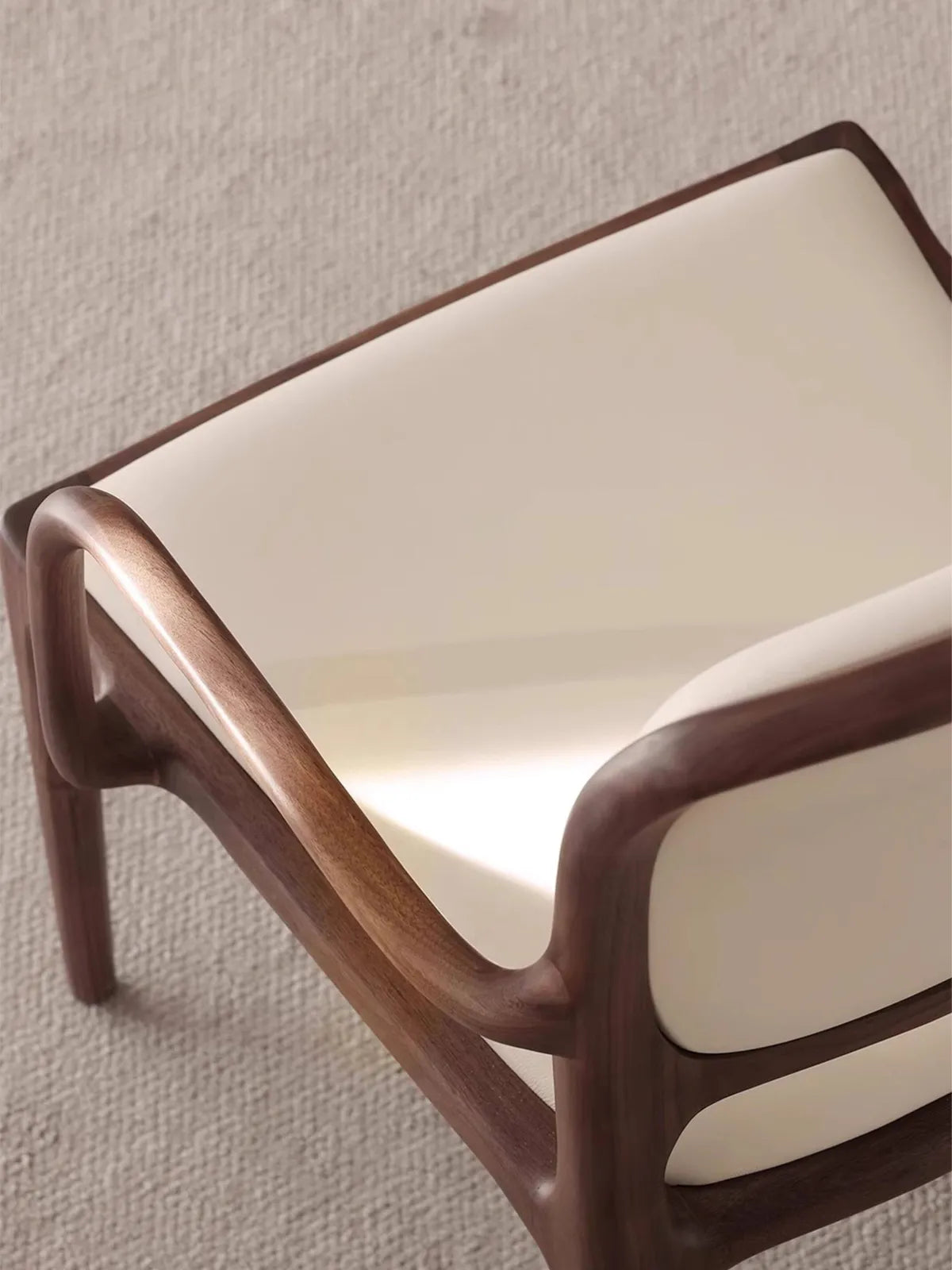 Close-up of the Cael arm chair walnut frame showing rich natural grain and zero-VOC hard wax oil finish.