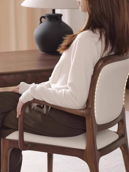 Side view of a person seated in the Cael arm chair at a desk, showing armrest height and backrest support in use.