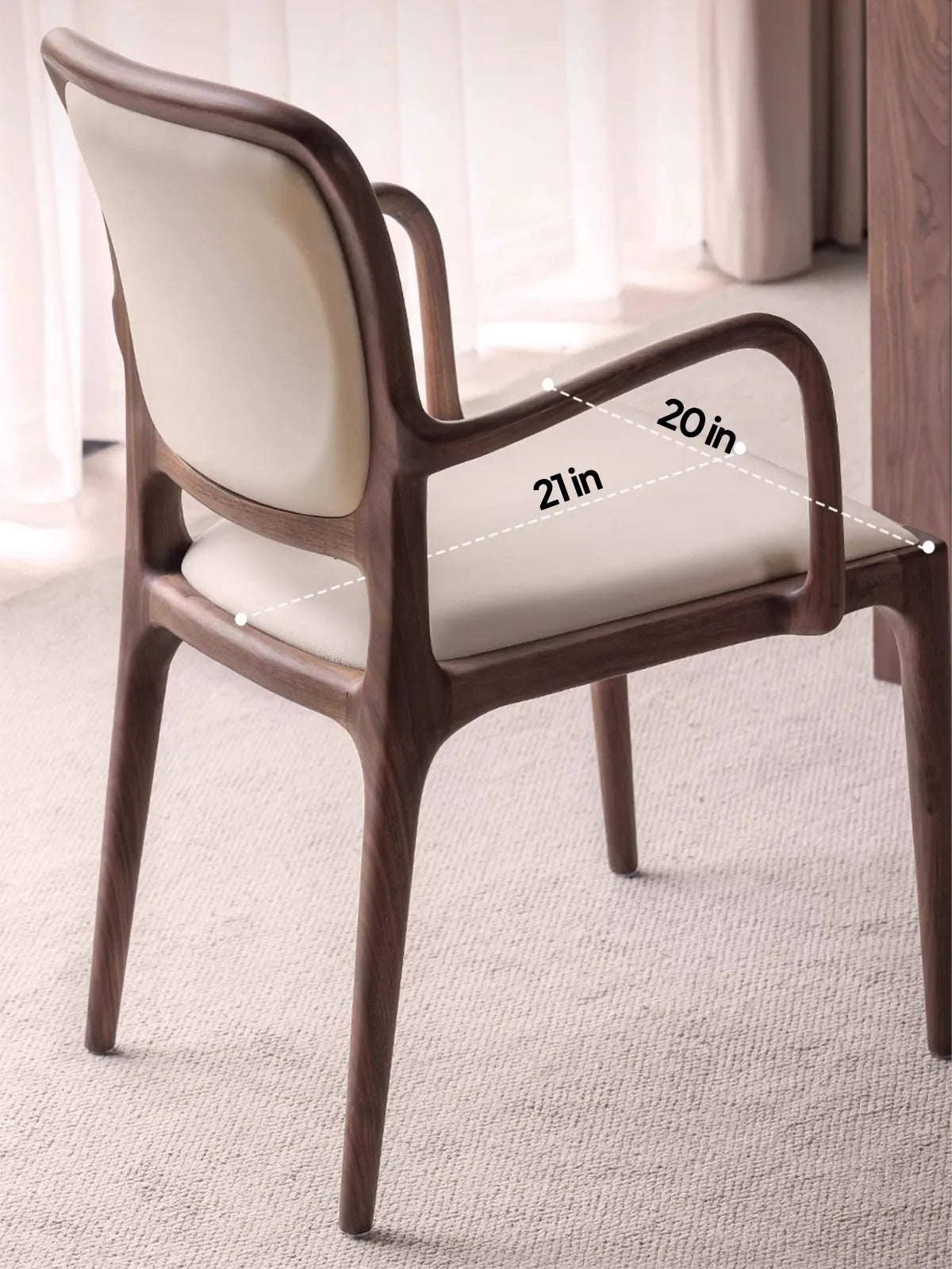 Three-quarter angle of the Cael dining arm chair highlighting the organic modern silhouette and cream upholstery.