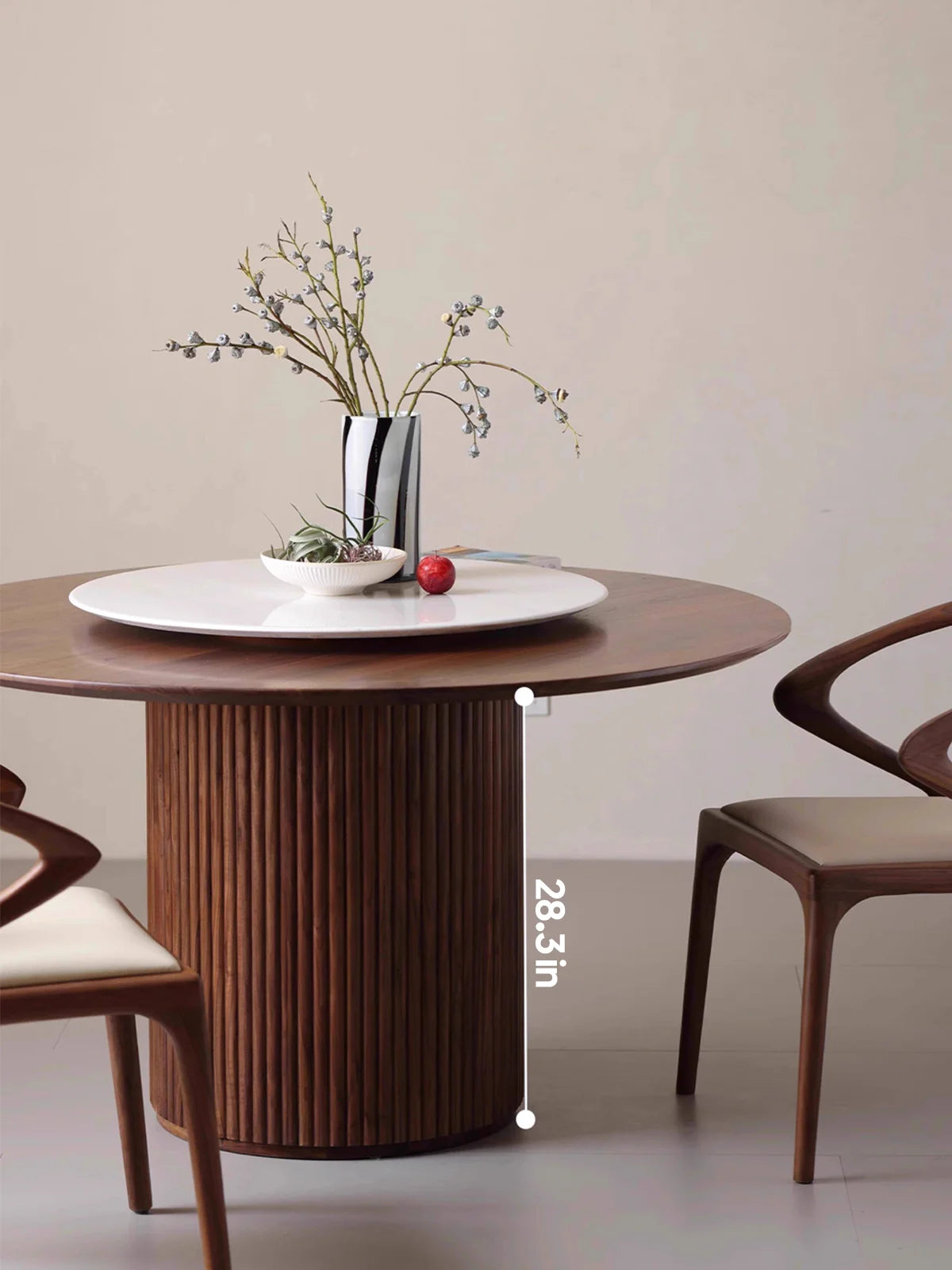 Front view of the walnut round pedestal dining table with white lazy Susan and floral vase, showing the table height.