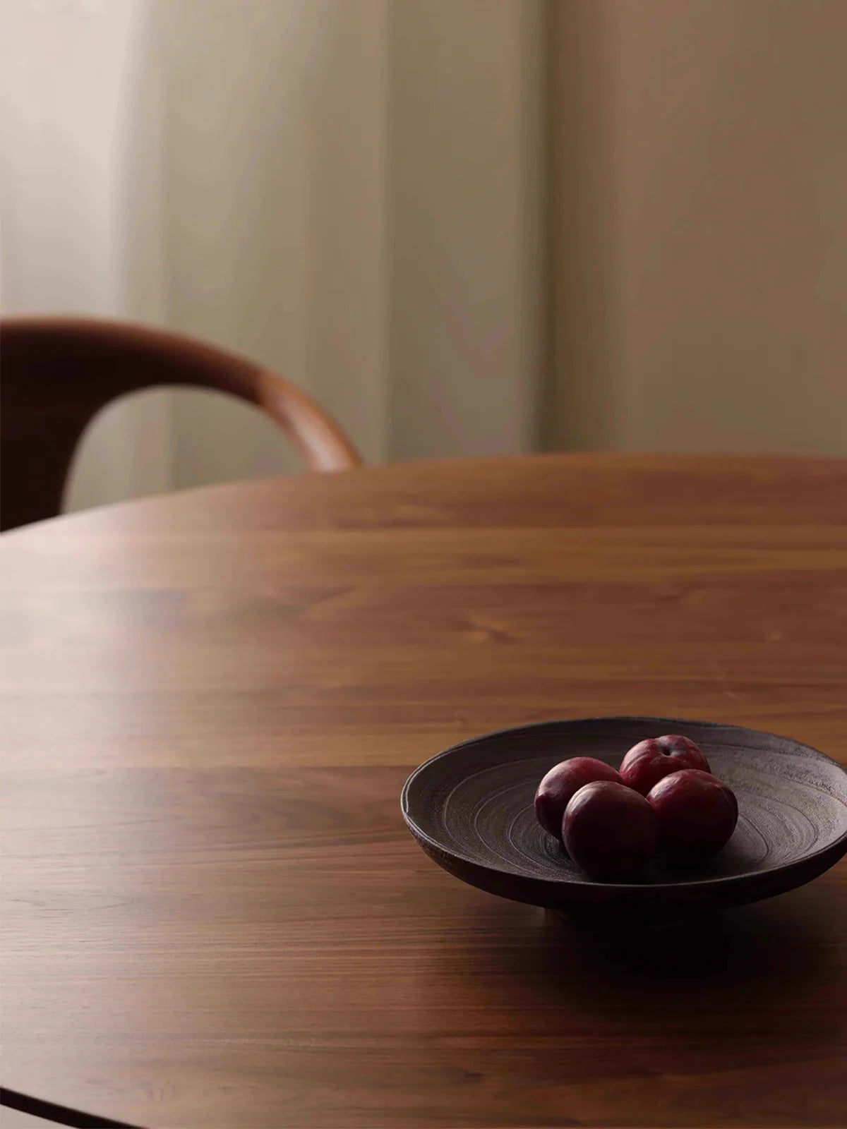Close view of the walnut tabletop grain with a shallow dark bowl placed near the edge.