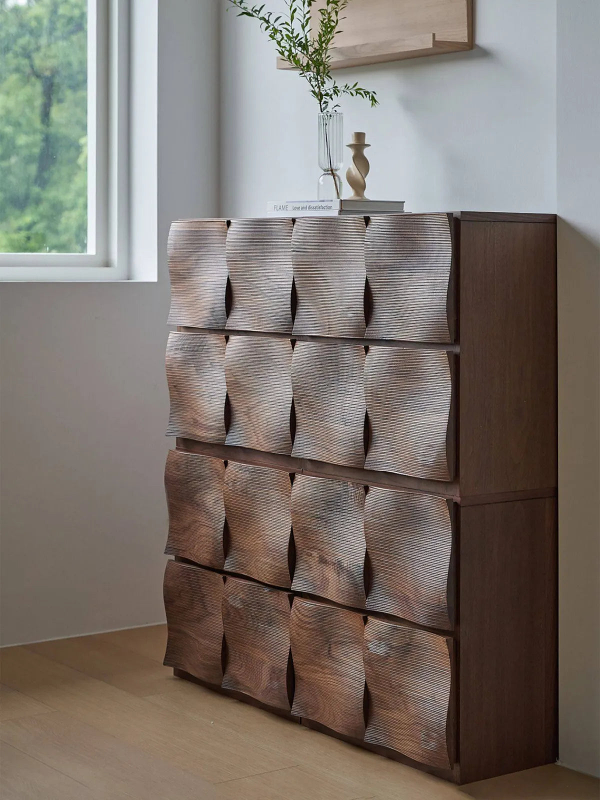 Side view of Walnutry Cumberland solid walnut chest showing deep sculpted wave texture and organic modern profile in a minimalist bedroom.