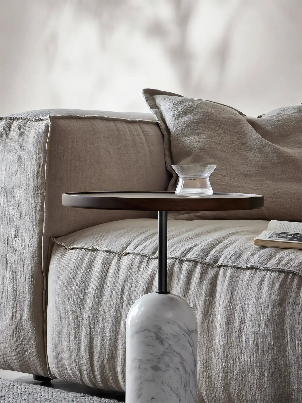 Solid black walnut side table styled next to a linen sofa in a modern living room, showing pedestal design.