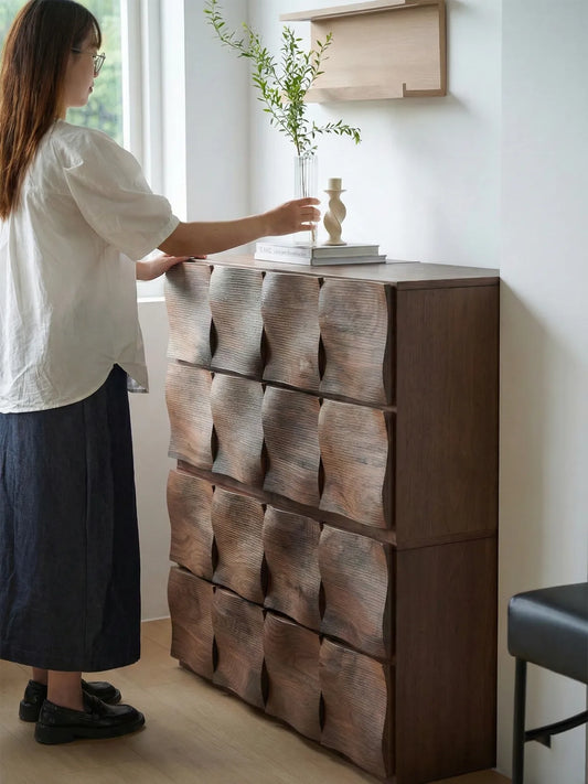 Woman arranging flowers on a Walnutry Cumberland solid walnut dresser, demonstrating height and scale in a biophilic home setting.