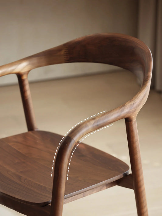 close-up detail of the sculpted curved arm and back frame in solid walnut