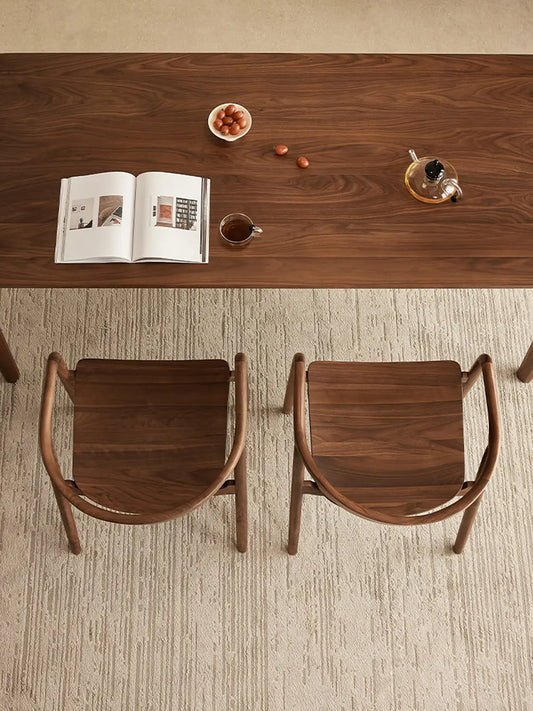 overhead view of two curved back walnut dining chairs tucked under a walnut dining table