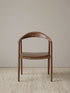 front view of a curved back walnut dining chair with wraparound backrest and sculpted seat