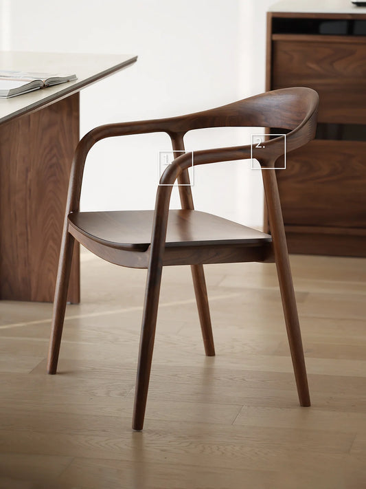 side profile of a curved back walnut dining chair beside a walnut table