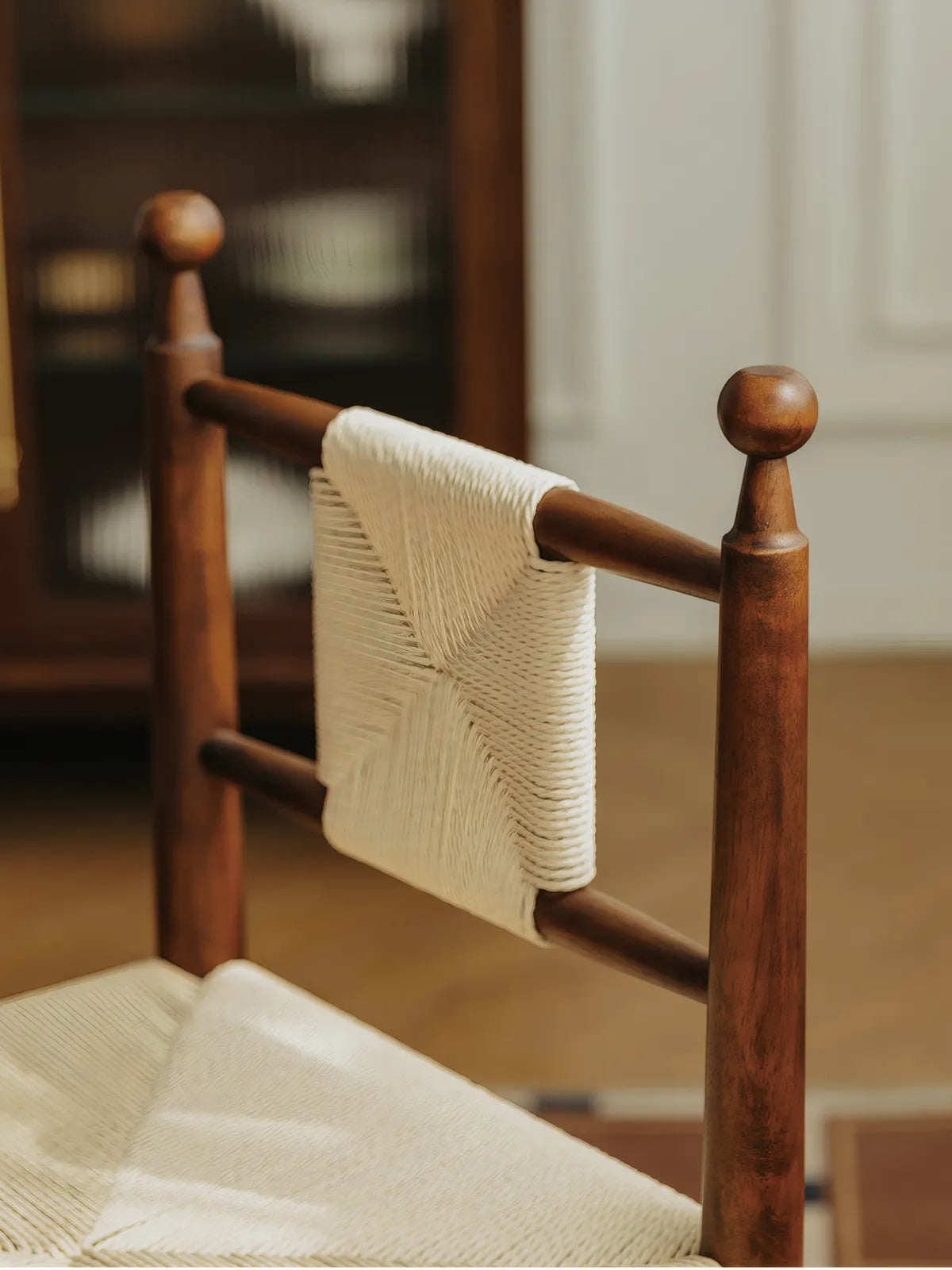 Rear detail of the Daren chair showing woven cord backrest panel and walnut finial posts