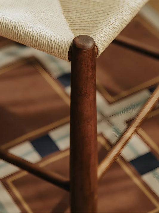Close-up of turned walnut leg and paper cord seat joint on the Daren dining chair