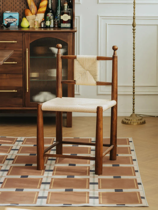 Three-quarter rear view of the Daren walnut dining chair with paper cord weave in styled interior
