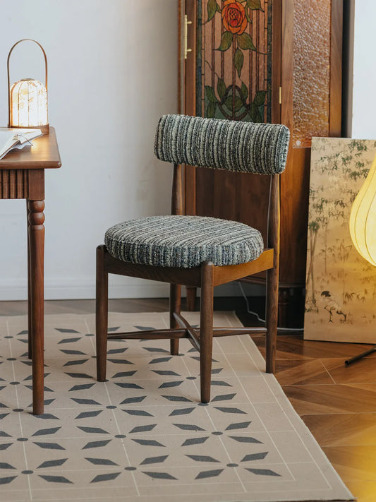 Eron walnut dining chair in a styled room with stained glass panel and patterned tile rug, front angle