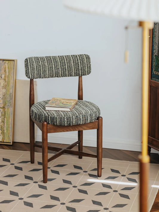 Eron walnut dining chair styled on patterned tile floor with books on the seat, three-quarter front angle