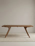 Front view of the Estate solid walnut dining table highlighting its balanced proportions and angled leg silhouette.