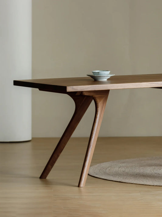 Close-up of the Estate dining table leg joinery, showing the sculpted under-table support and solid walnut construction.