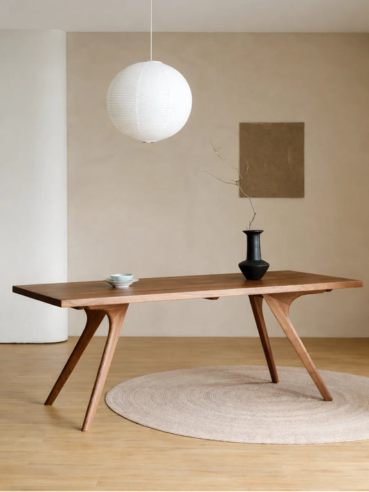 ront angled view of the Estate rectangular walnut dining table styled with a ceramic bowl, black vase, and round woven rug.