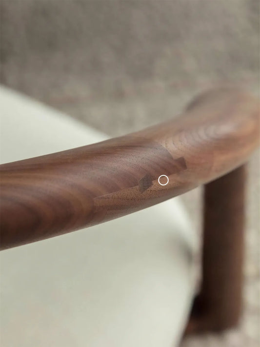 A macro detail shot highlighting the precise, traditional wood joinery on the solid walnut frame of The Haven Wide-Seat Floor Chair.