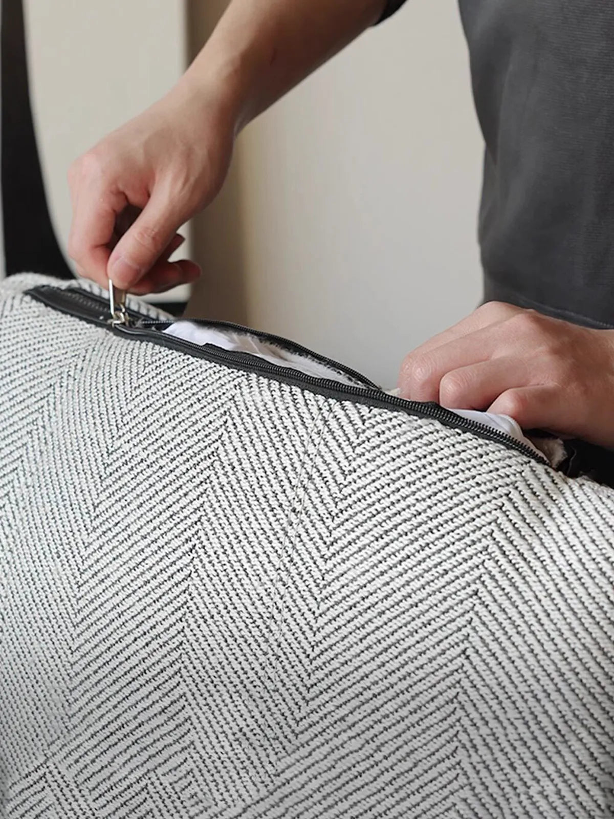 Hands unzipping the removable and washable cushion cover of this mid century modern reading chair.