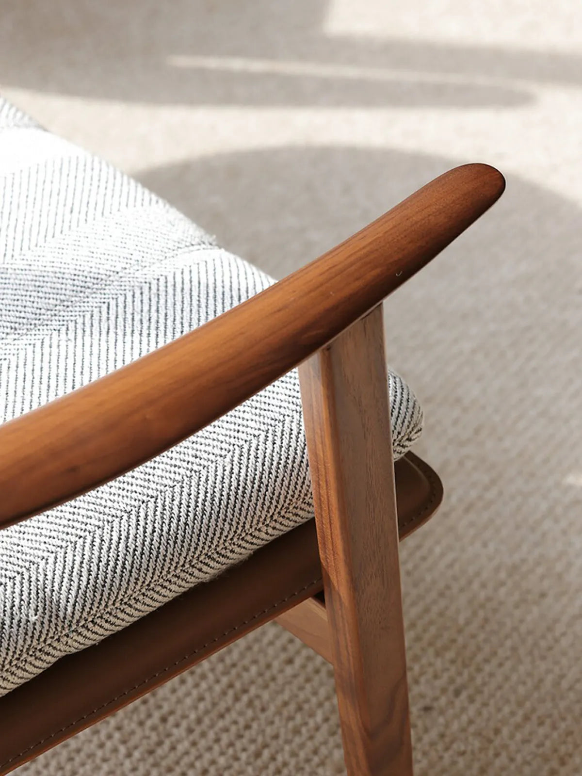Macro detail of the hand-rubbed wax oil finish on the solid wood chair armrest.