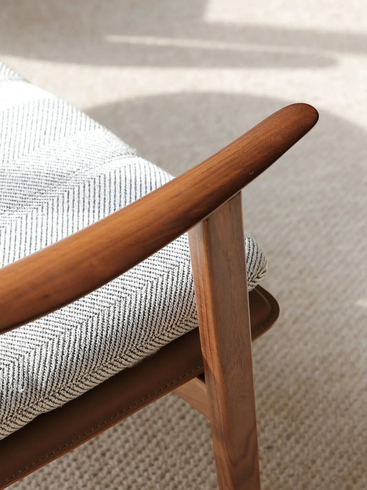 Macro detail of the hand-rubbed wax oil finish on the solid wood chair armrest.