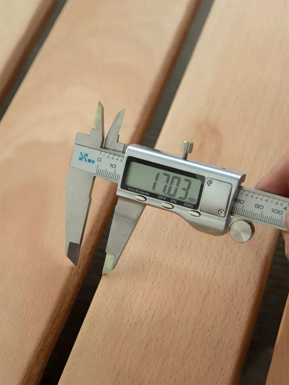 Close-up of a digital caliper measuring the 17mm thick solid North American Black Walnut planks used in The Helios Bed Frame construction.