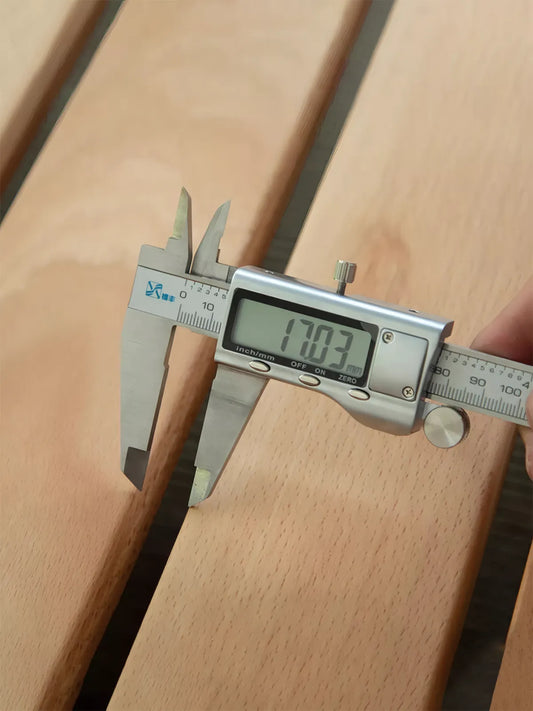Close-up of a digital caliper measuring the 17mm thick solid North American Black Walnut planks used in The Helios Bed Frame construction.