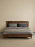 Straight-on studio view of The Helios Bed Frame by Walnutry, featuring a clean mid-century design crafted entirely from premium solid walnut.