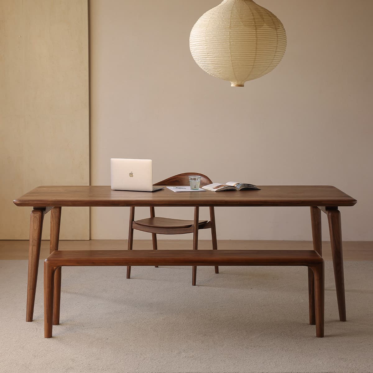 Complete Walnutry Helios dining set featuring a solid black walnut table, bench, and chairs in a warm modern dining room setting with pendant lighting.