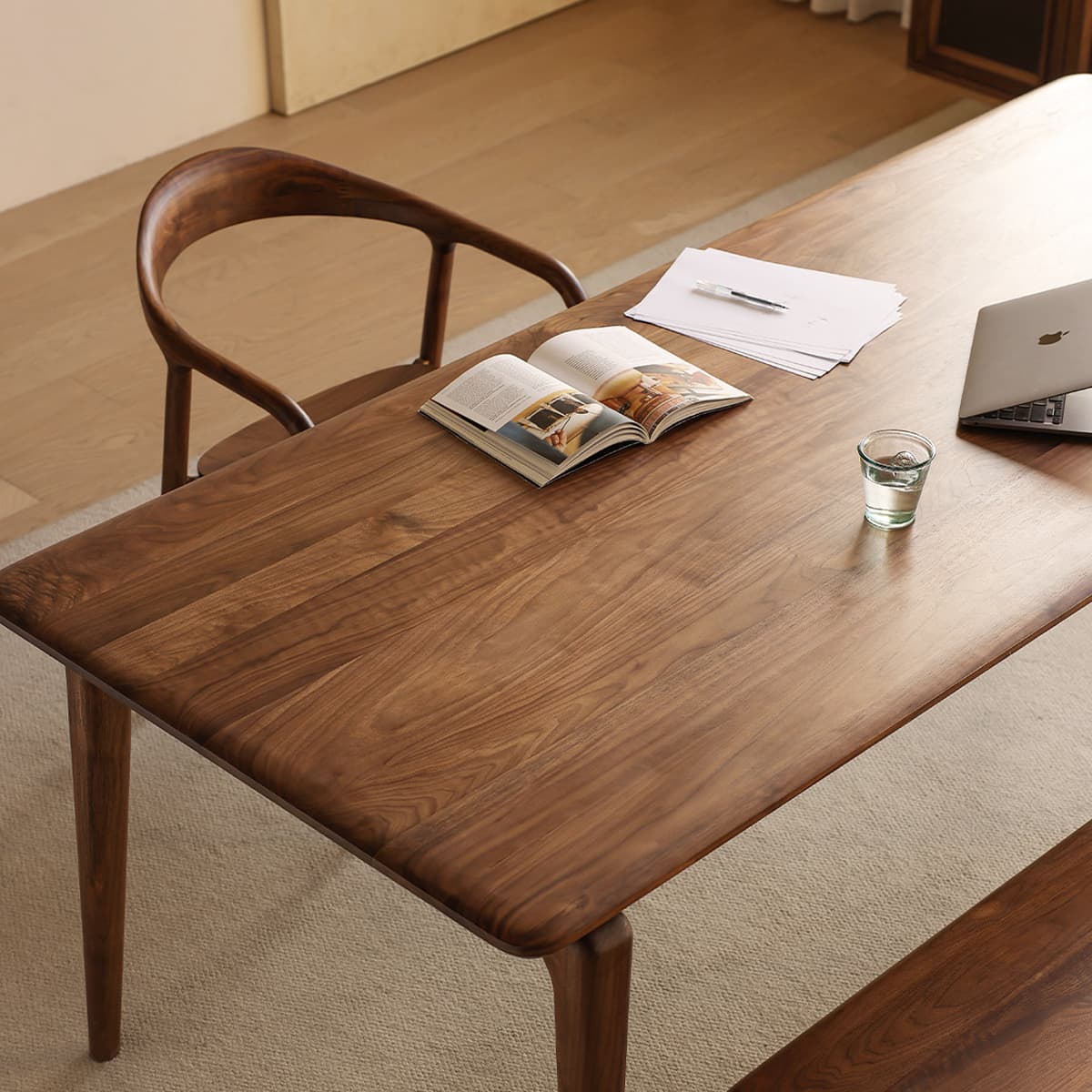 Close-up top view of the Walnutry Helios dining table, highlighting the rich North American black walnut wood grain texture and smooth handcrafted edge profile.