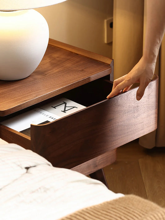 A hand smoothly opening the top drawer of The Helios Nightstand, highlighting the solid wood craftsmanship and seamless integrated handle design.