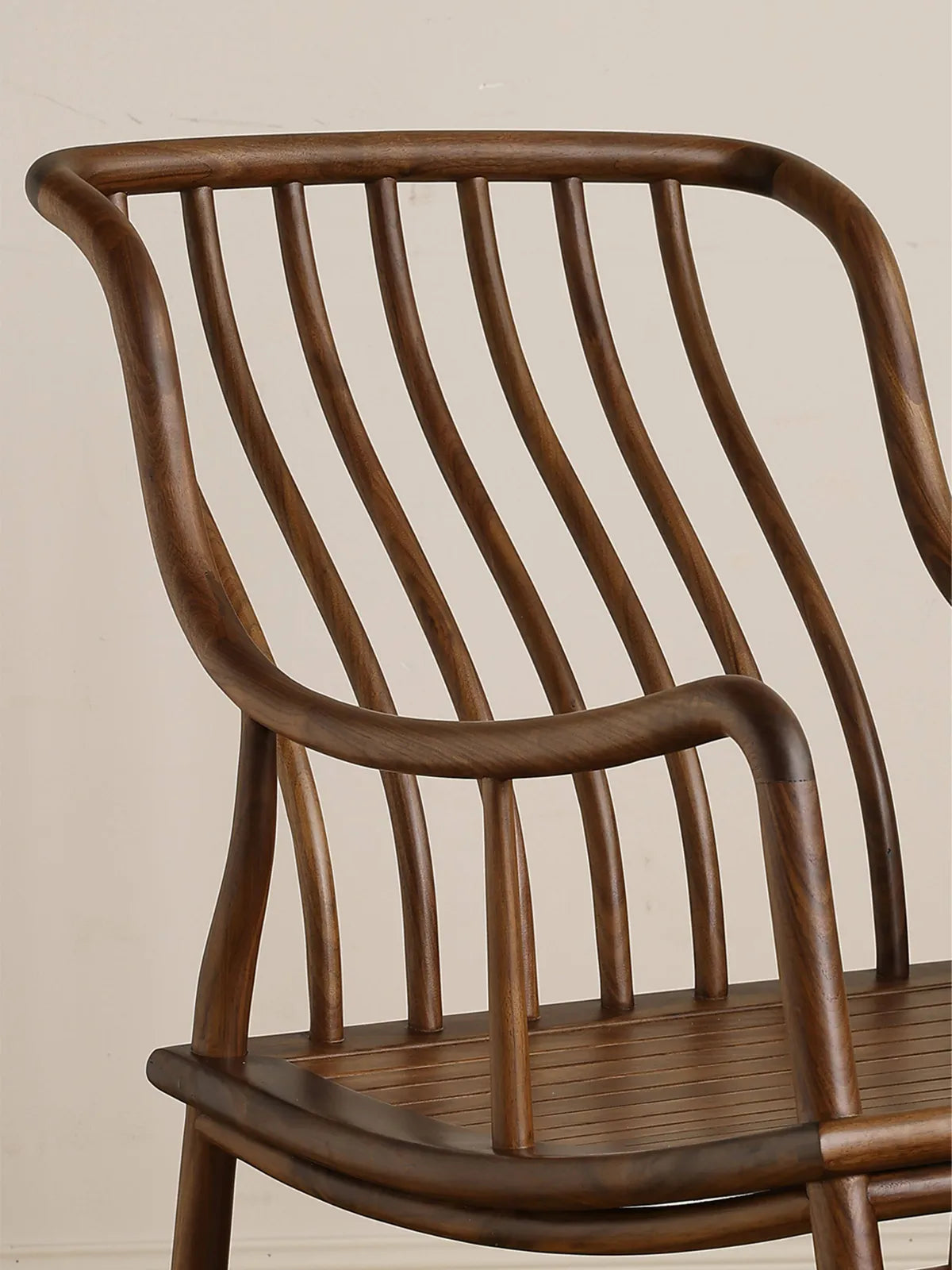Close-up view of the gracefully curved spindle backrest and smooth, rounded armrests crafted entirely from premium North American Black Walnut.