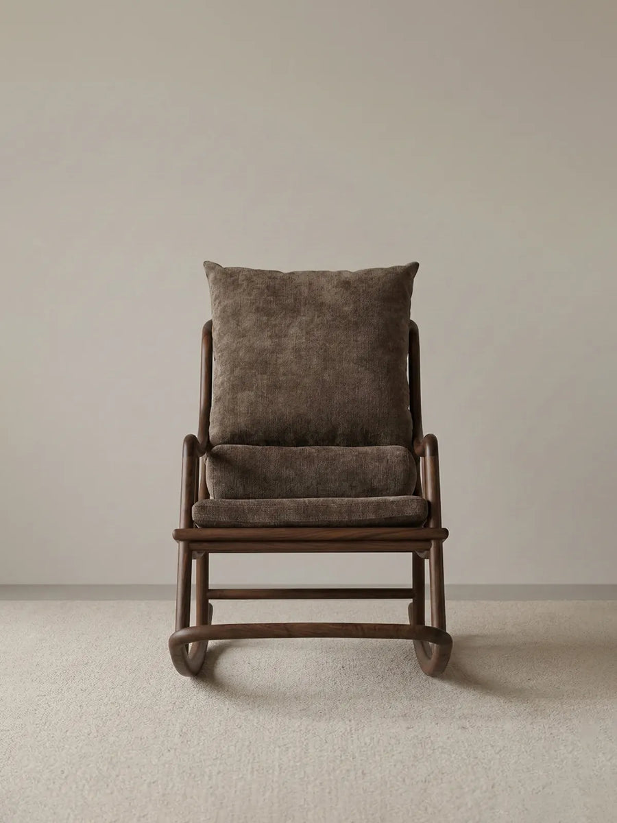 Straight-on studio shot of The Helios Rocking Chair showcasing its balanced mid-century modern proportions, brown upholstery, and rich walnut wood base.