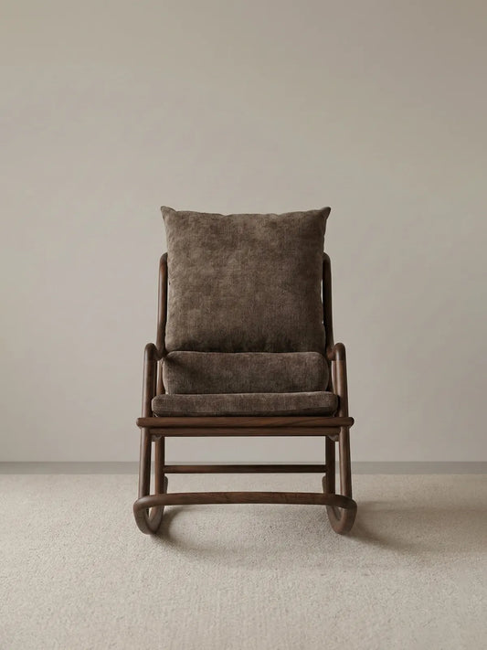 Straight-on studio shot of The Helios Rocking Chair showcasing its balanced mid-century modern proportions, brown upholstery, and rich walnut wood base.