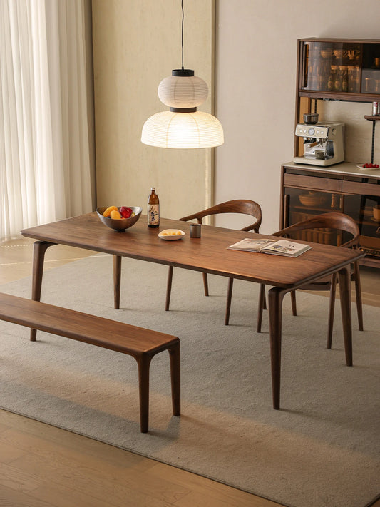 The Helios solid wood dining table and bench elegantly paired with matching chairs in a modern minimalist dining room.