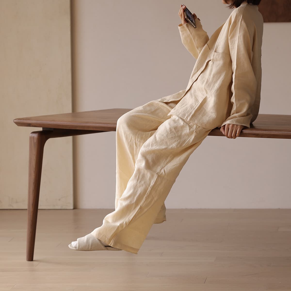 Lifestyle image showing the sturdy solid wood construction of the Walnutry Helios dining table with a person sitting on the edge, emphasizing durability and premium finish.