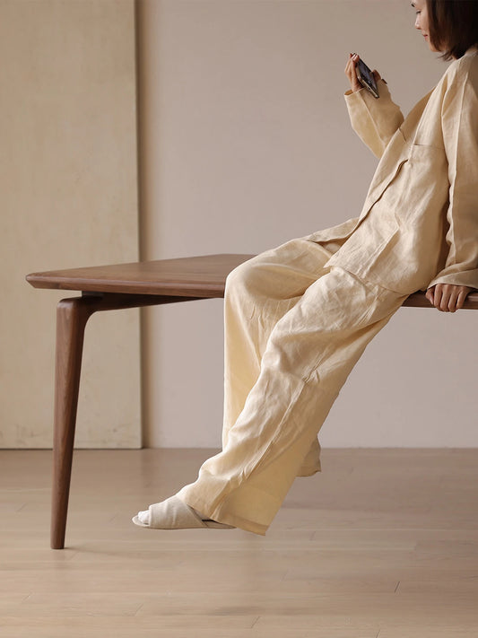 A woman relaxing comfortably on the edge of the sturdy walnut dining room table, showcasing its solid construction and anti-wobble design.