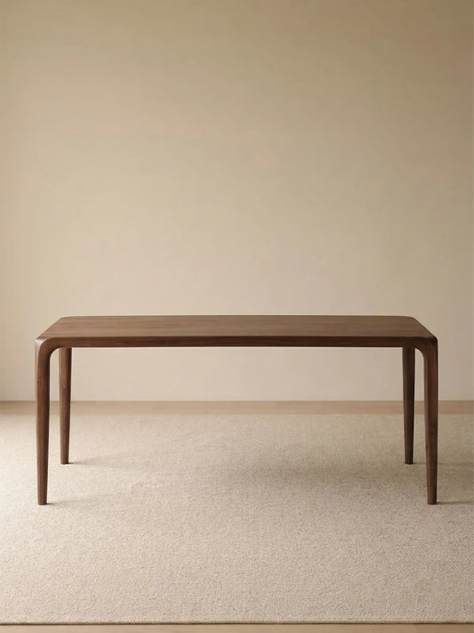 Front studio view of the Heritage black walnut dining table, featuring an organic modern silhouette and tapered legs.