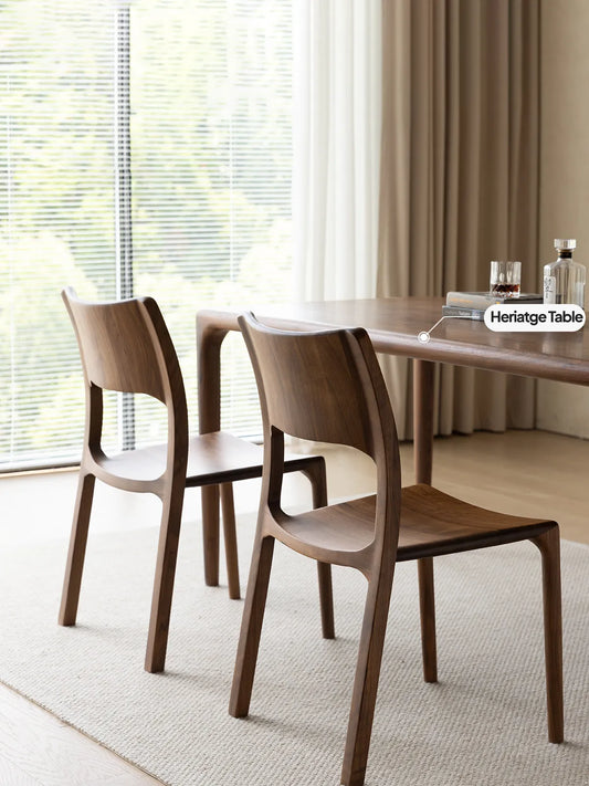 Two solid black walnut Heritage Dining Chairs paired with the matching Heritage wooden dining table in a bright, minimalist dining room.