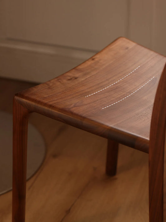 Close-up of the contoured solid walnut seat on The Heritage Dining Chair by Walnutry, highlighting its ergonomic carved design with dashed lines.