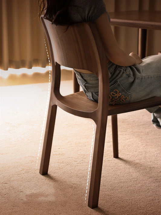 A person sitting comfortably in The Heritage Dining Chair, with dashed lines illustrating the excellent ergonomic back support and leg posture.