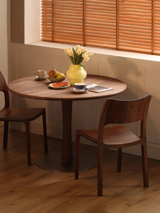 Two Walnutry Heritage Dining Chairs styled with a round wooden table, a yellow vase with tulips, and fresh fruit in a cozy dining nook.