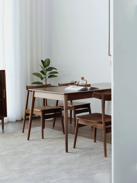 Solid wood extendable dining table in walnut styled in a calm dining space with soft rug and modern chairs